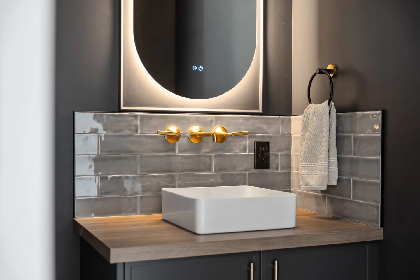 Powder room vanity with backlit mirror and brass faucet